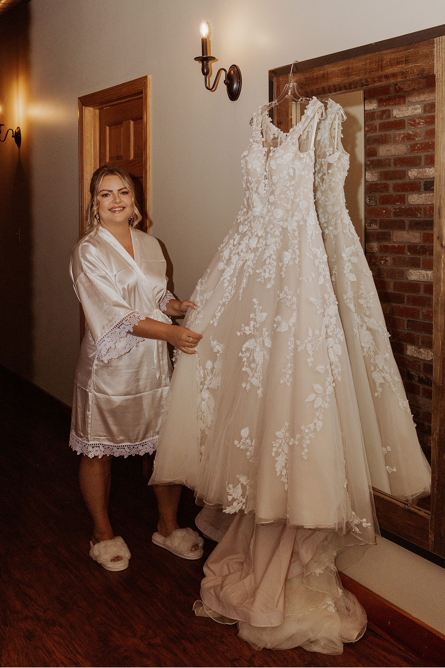 Wedding dress preparation in a rustic room with exposed brick and warm lighting.