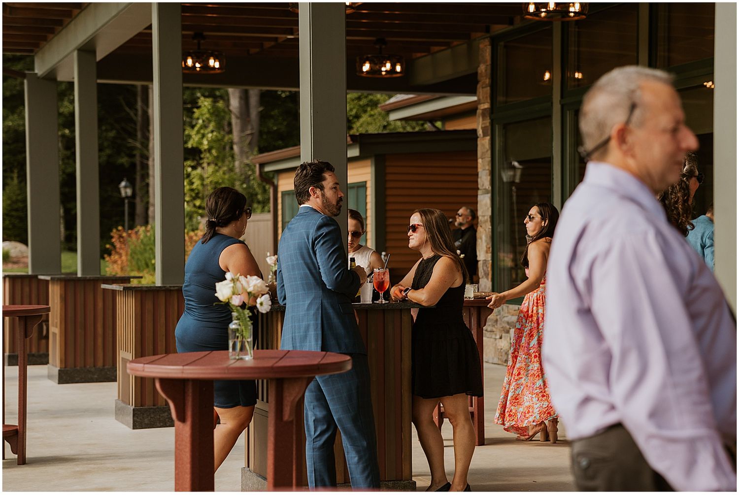 Guests mingling at an outdoor covered patio area during a wedding reception.