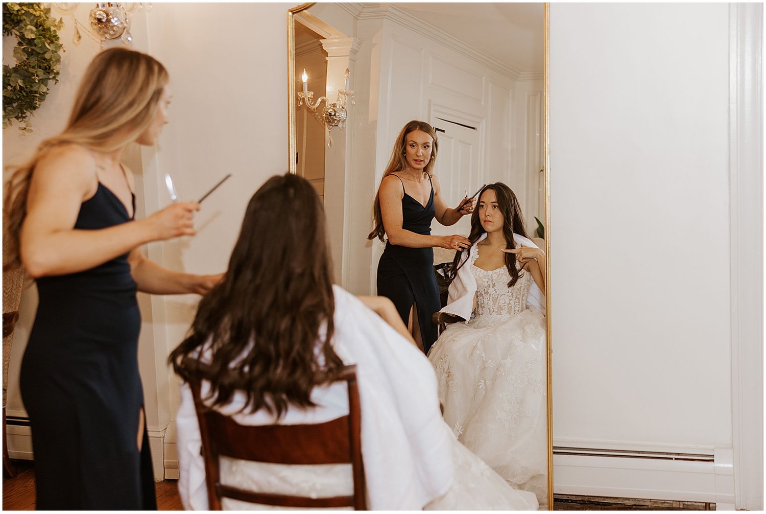 Getting ready scene with white wedding dress visible in elegant room.