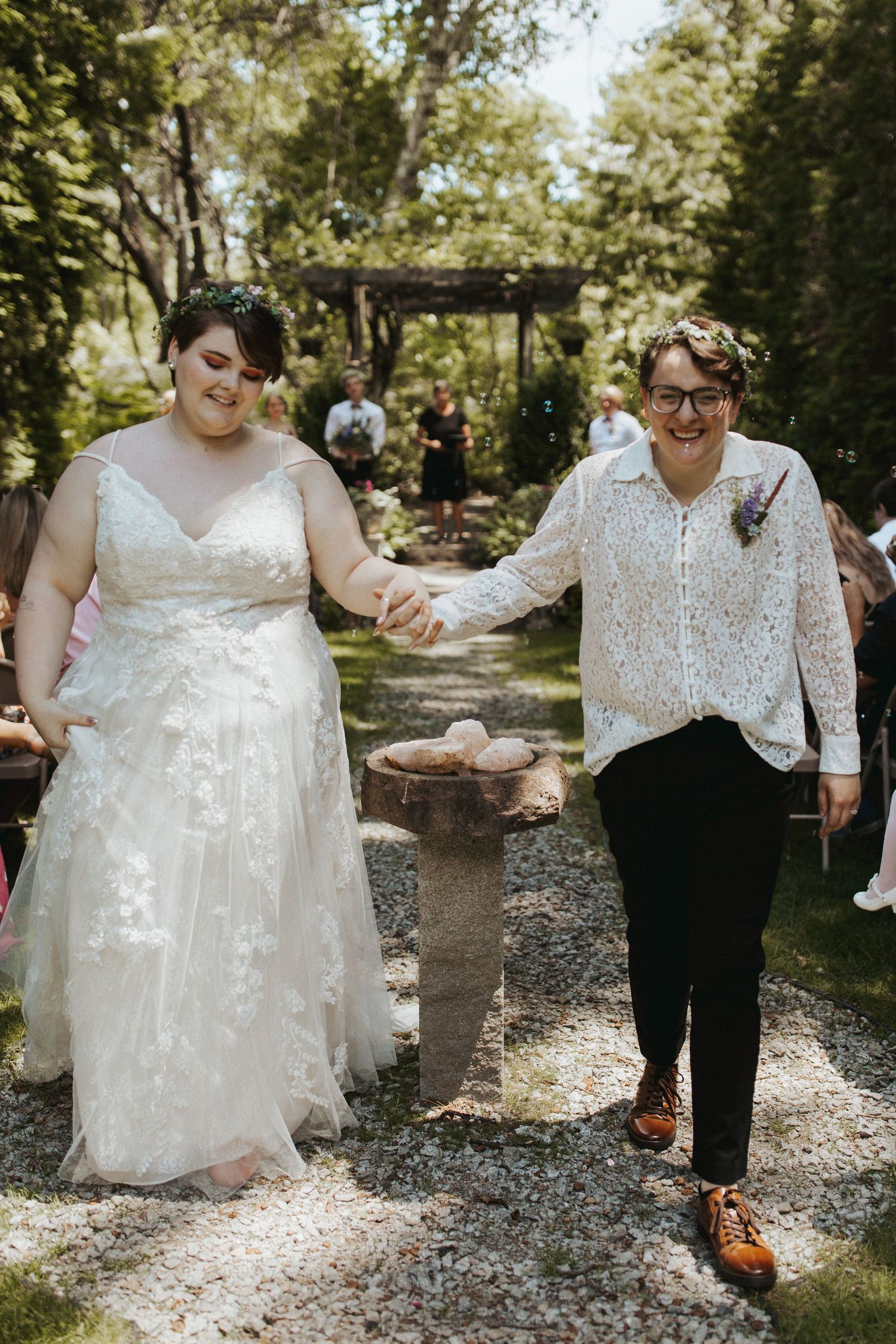 A couple shares a joyful moment while walking together on a tree-lined gravel path.