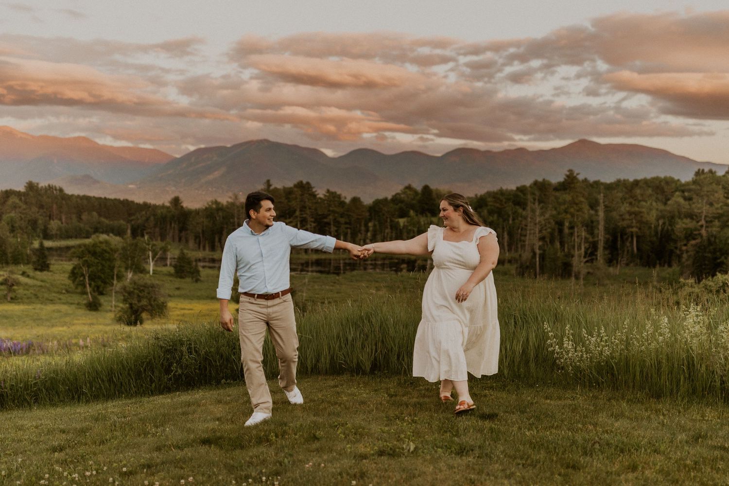 Terise and Jose playfully walking together in a lupine field in Sugar Hill NH during their engagement photos.