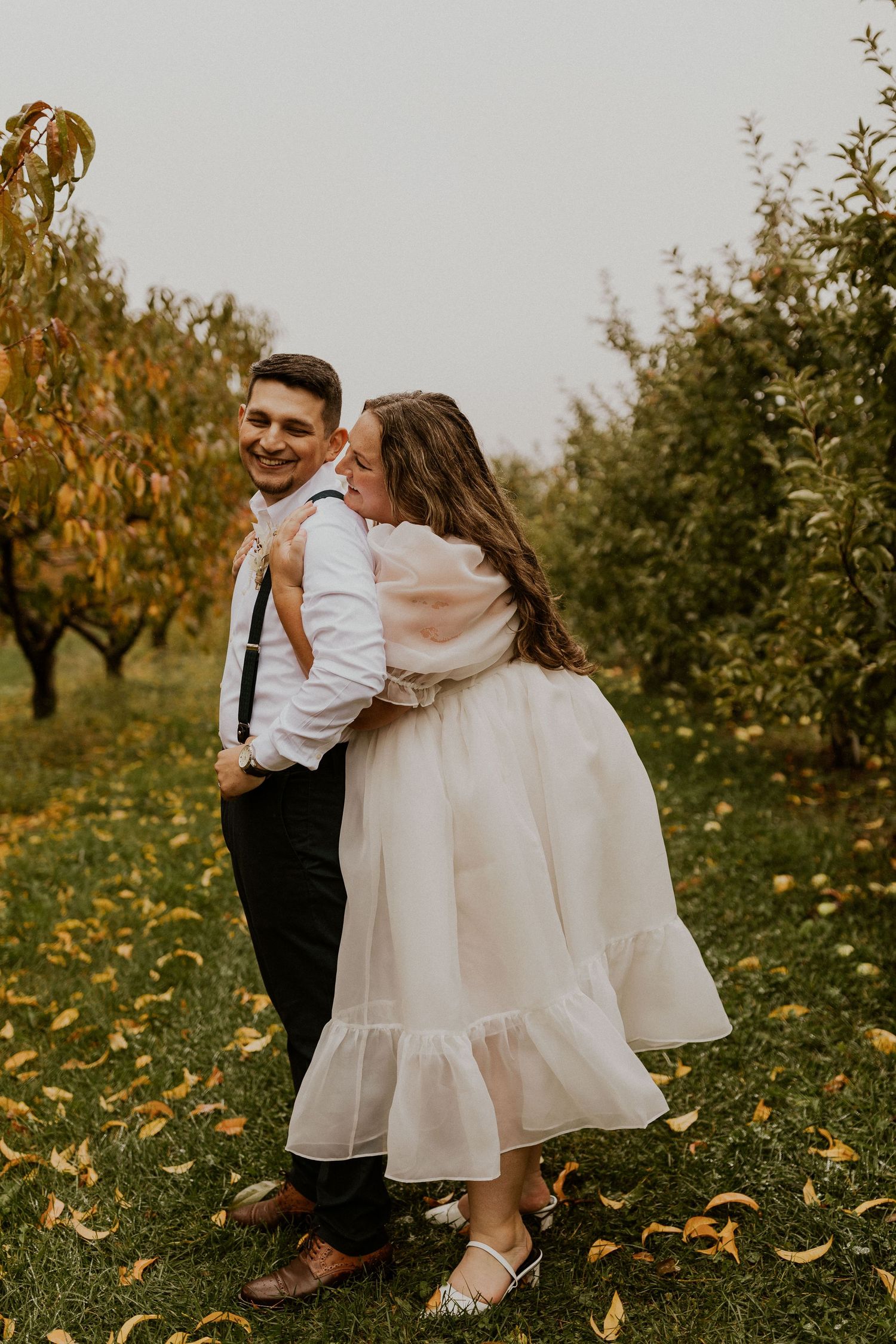 Terise and Jose kissing in between the rows of apple trees at Carter Hill Orchard in Concord New Hampshire]
