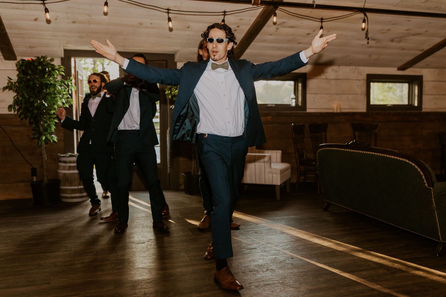 Wedding reception dancing in a rustic wooden venue with string lights overhead.