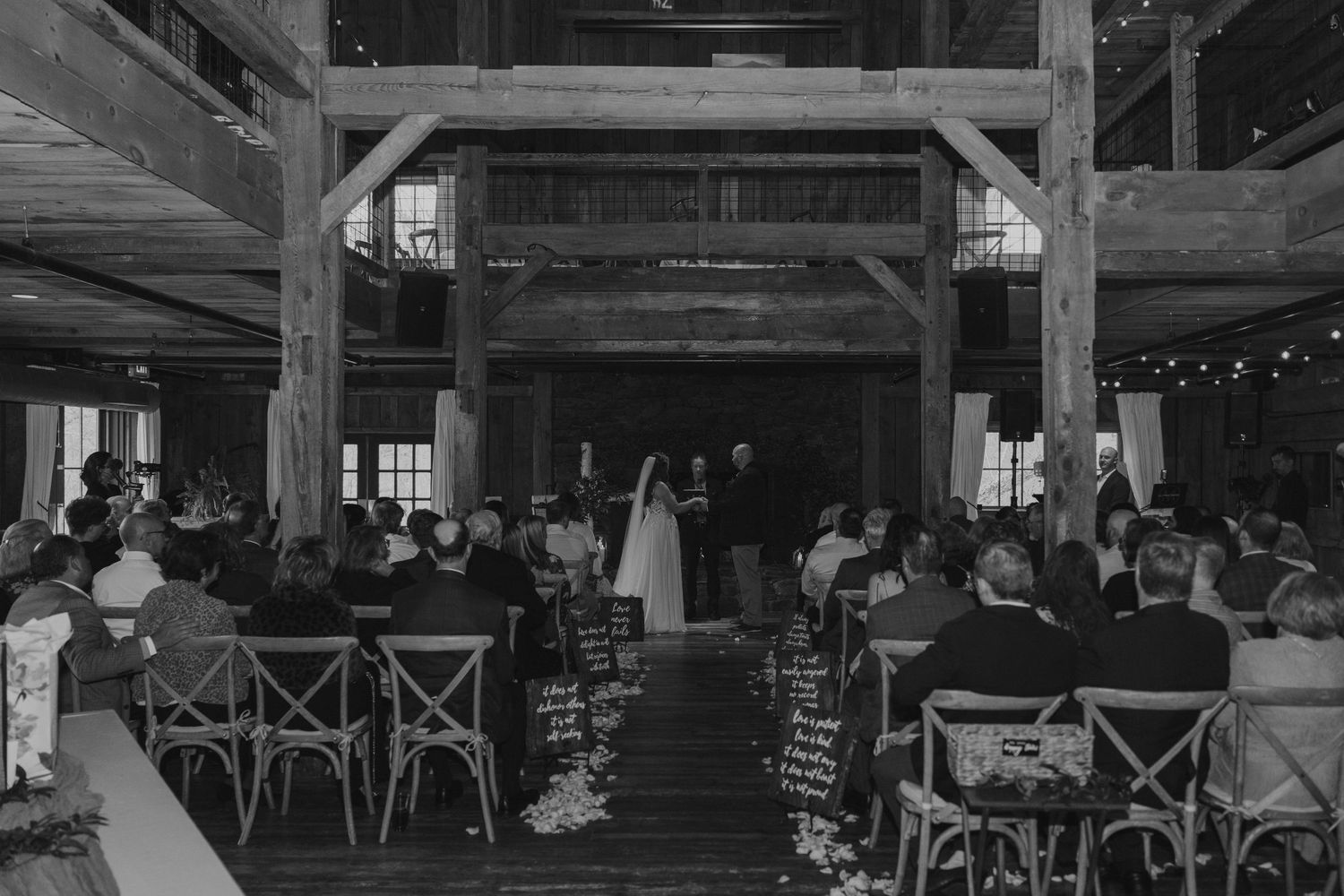 Large rustic barn reception venue with exposed wooden beams and guest seating.
