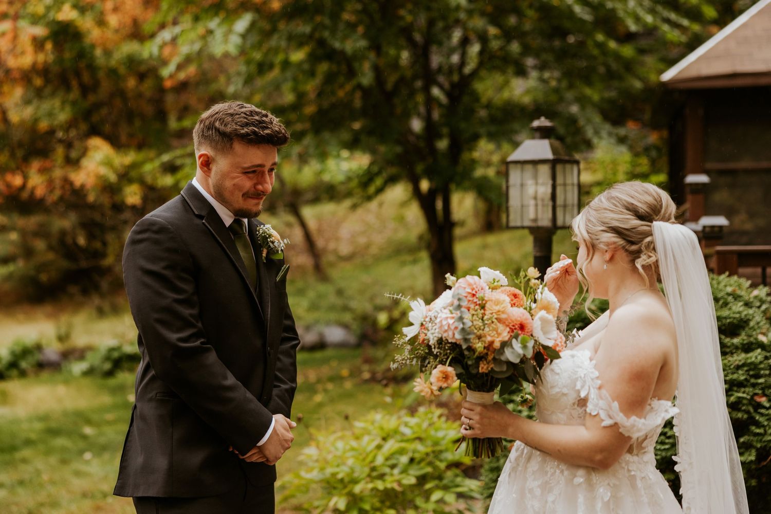 Emotional groom tears up seeing bride for first time during outdoor first look with autumn foliage.
