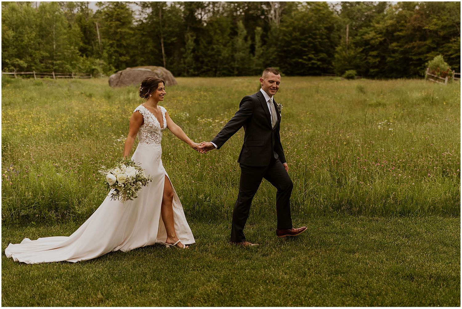 A couple dances and spins in a grassy field during their countryside wedding.