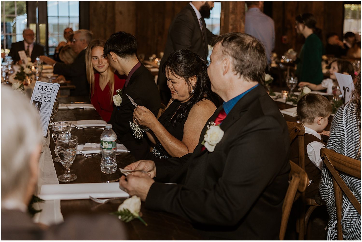 Reception guests enjoying dinner and conversation at decorated tables.