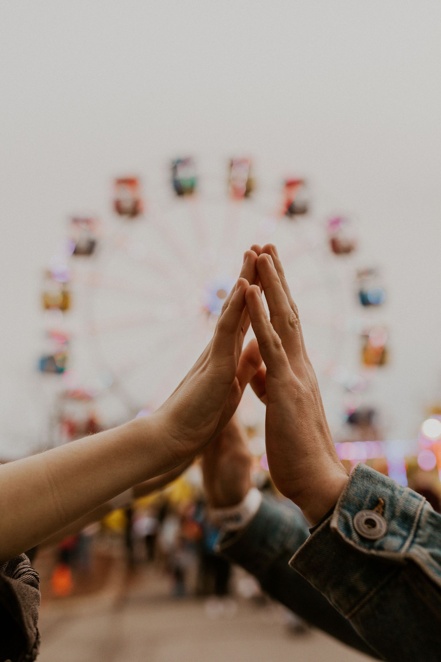 Hands joining together in a high-five against a blurred carnival background.