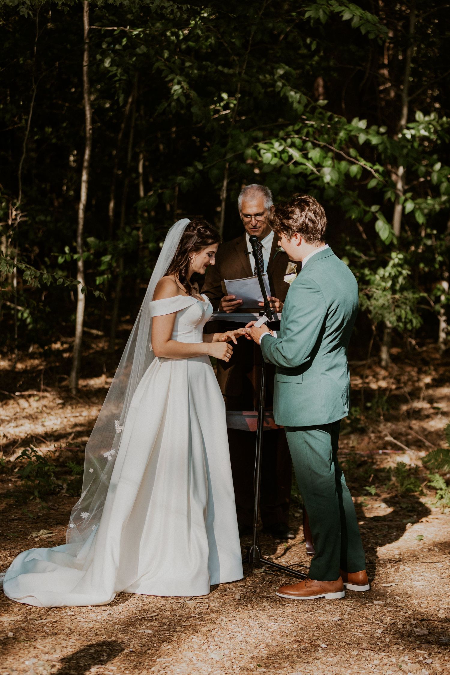Wedding ceremony moment captured in a sunlit forest setting.
