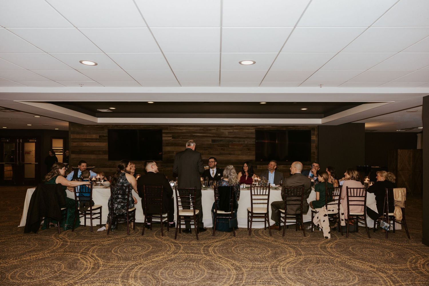 Wide angle shot of a wedding reception hall with guests seated at decorated tables.