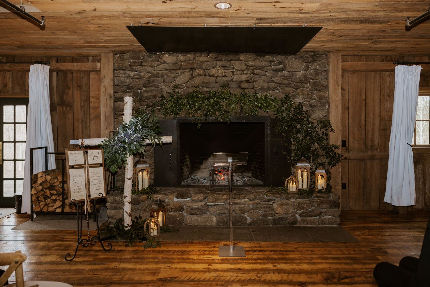 Rustic barn wedding venue interior with wooden beams and stone fireplace.