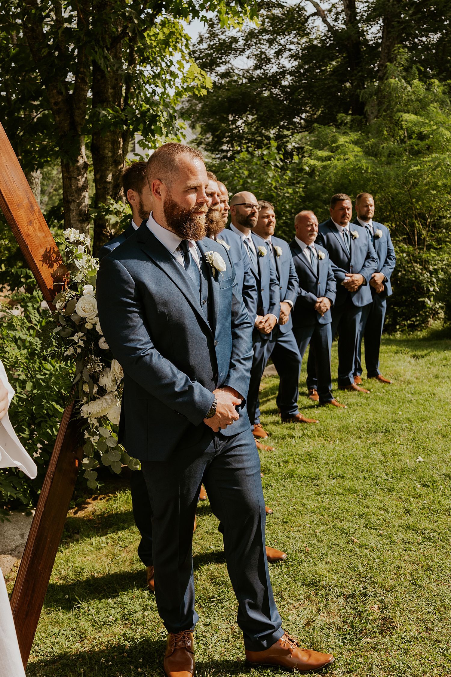 Groom in navy suit smiling at altar during outdoor wedding ceremony in New Hampshire - wedding photography advice