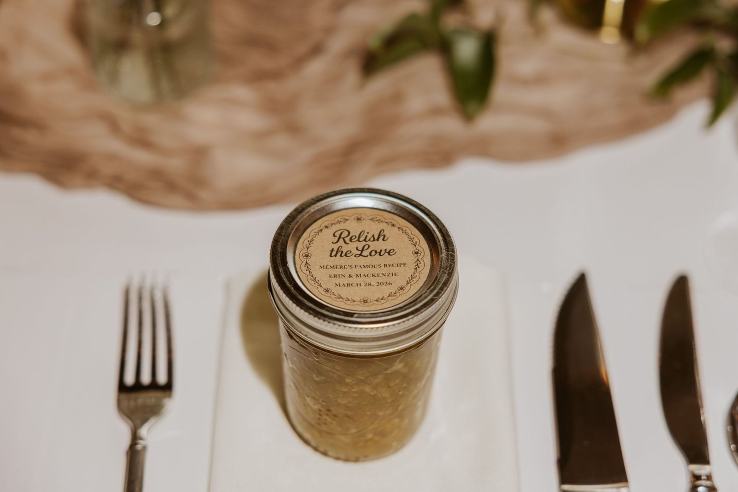 Wedding table place settings with rustic mason jar favors and vintage silverware.