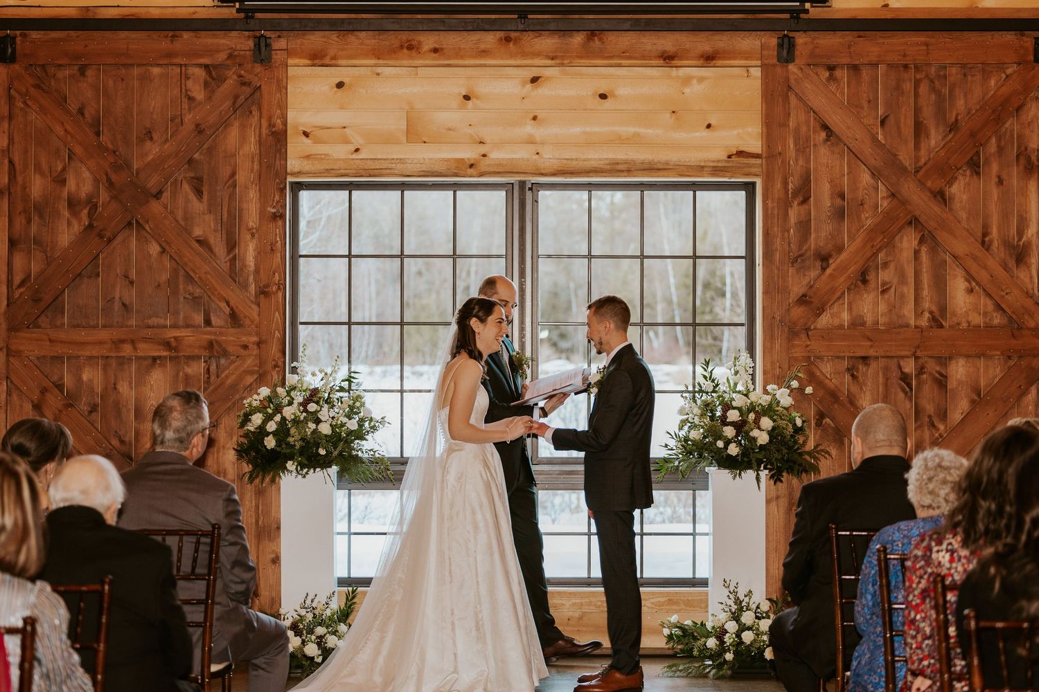 Rustic barn wedding ceremony setup with wooden beams and natural light streaming through windows.