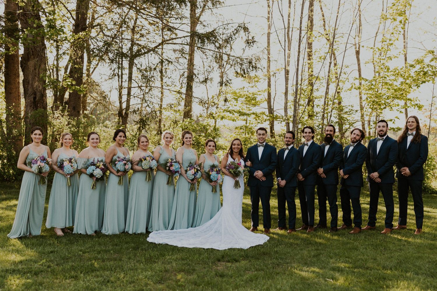 Entire wedding party standing and smiling together for a group portrait.