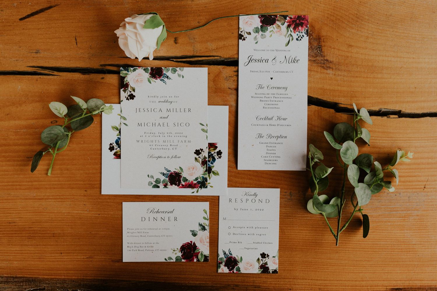 Flat lay photo including stationary and red and white roses on a wooden background.