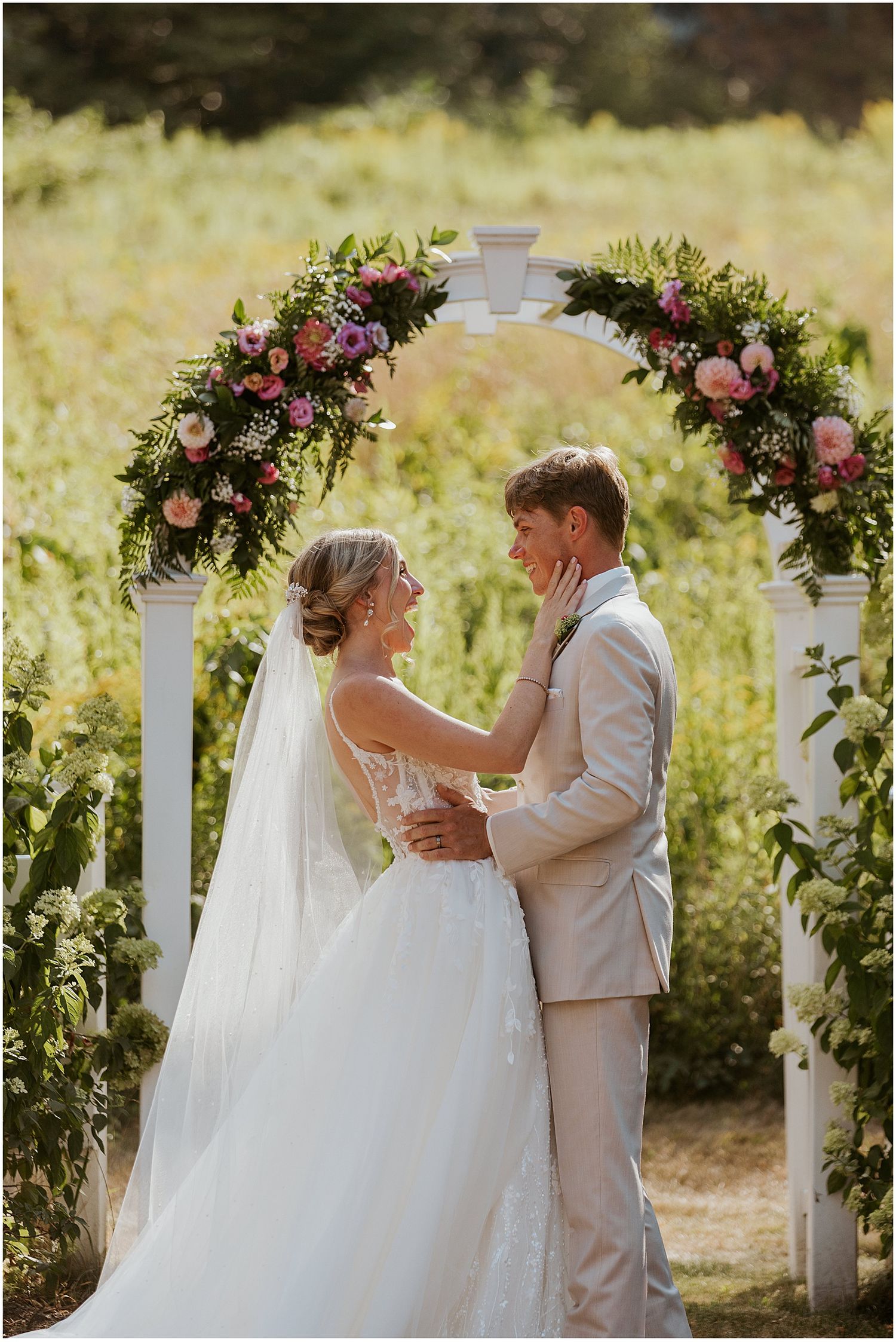 Couple embraces during their first look moment in a garden setting with floral decorations.