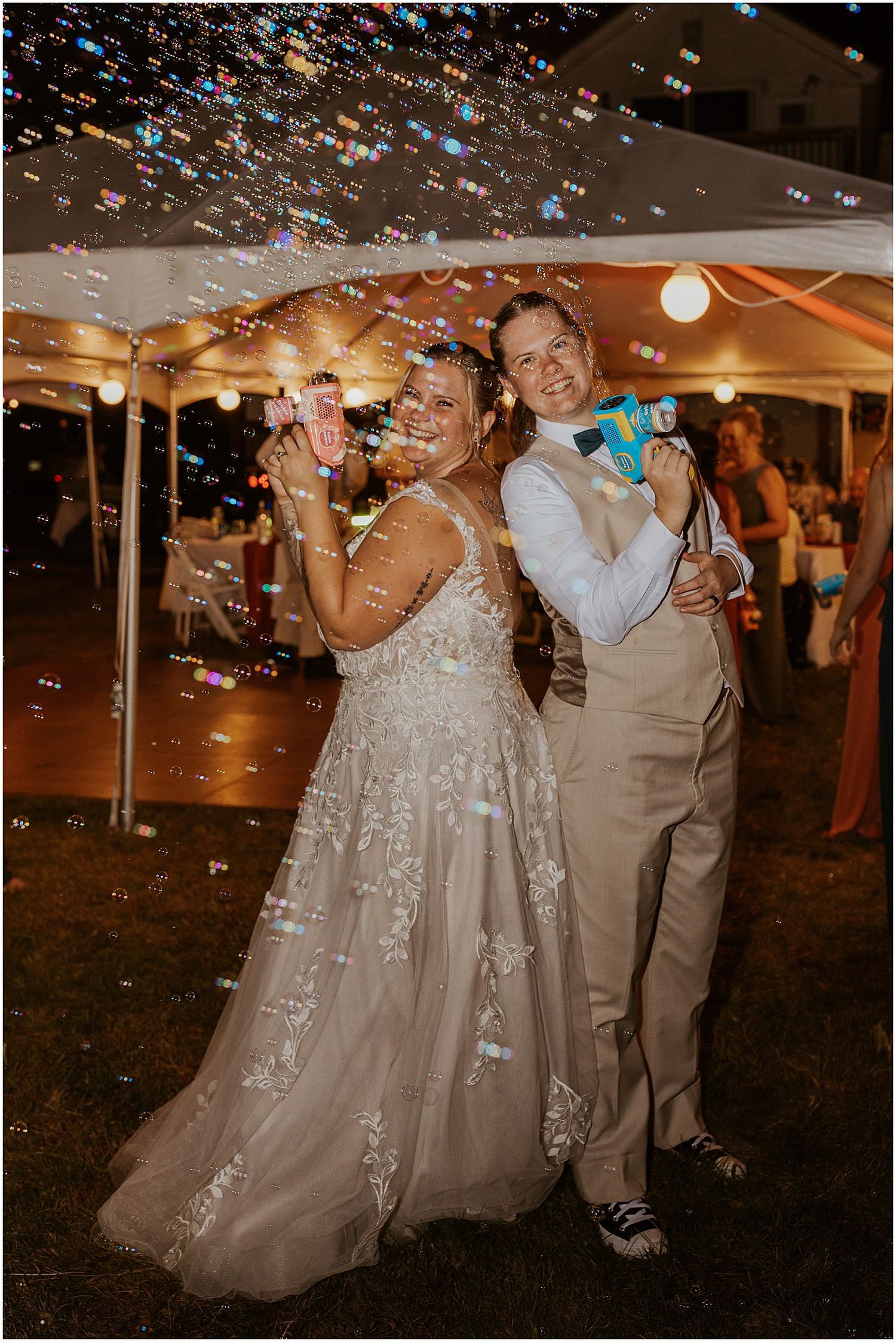 Couple dances under twinkling lights with confetti falling at outdoor evening reception.