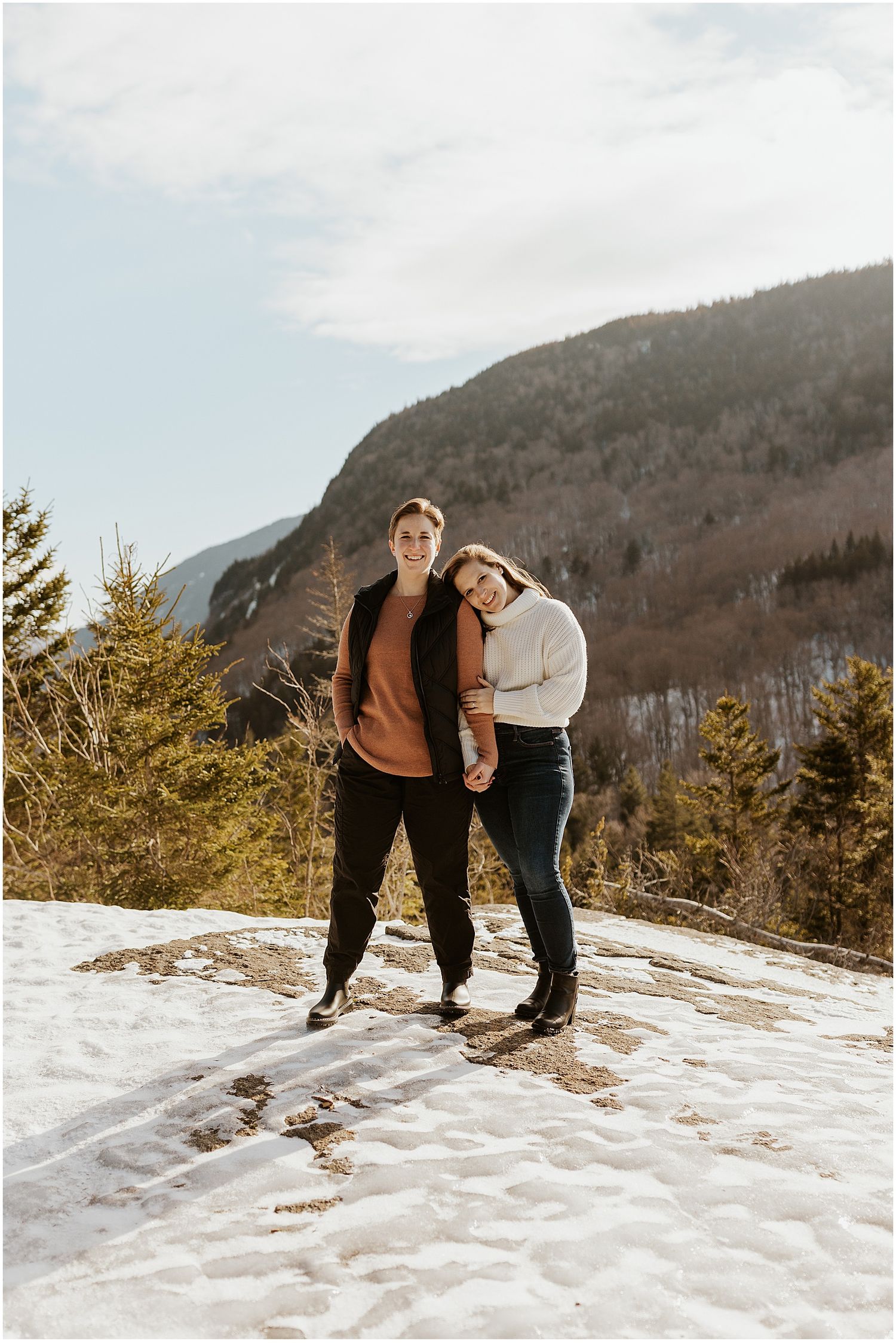 Couple enjoying a playful moment on snowy mountain terrain.
