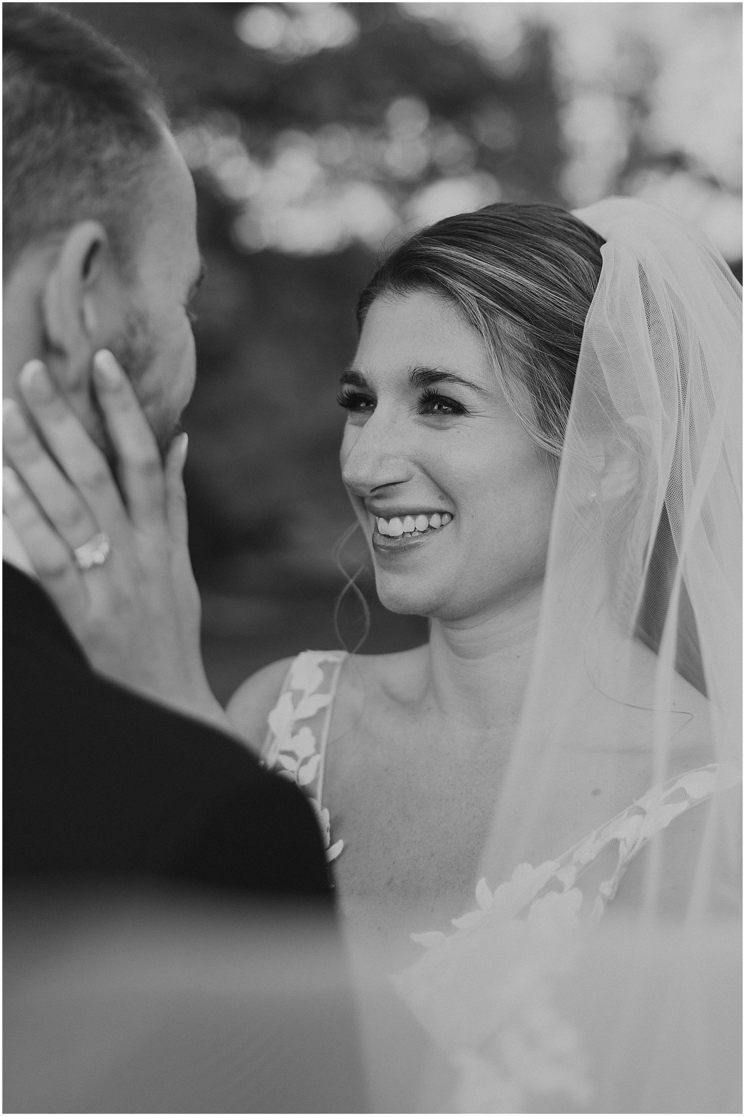 Black and white intimate moment between newlyweds sharing a tender smile during their wedding ceremony.