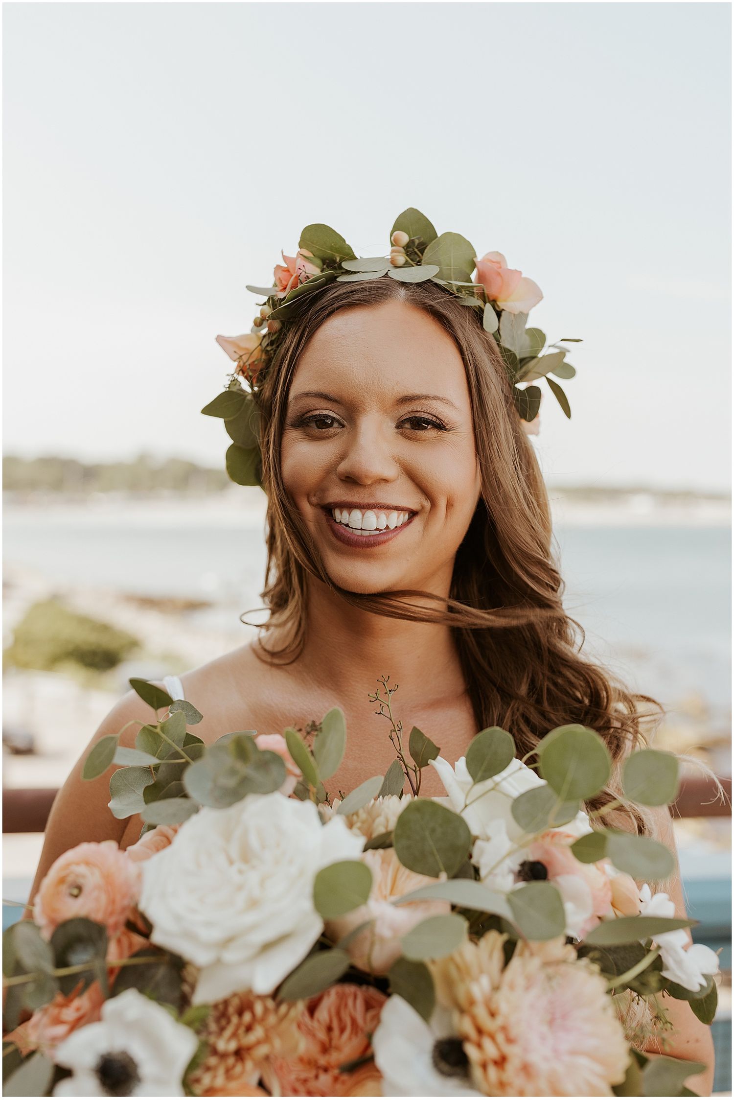 Beautiful floral arrangement with eucalyptus and roses against an oceanfront backdrop.