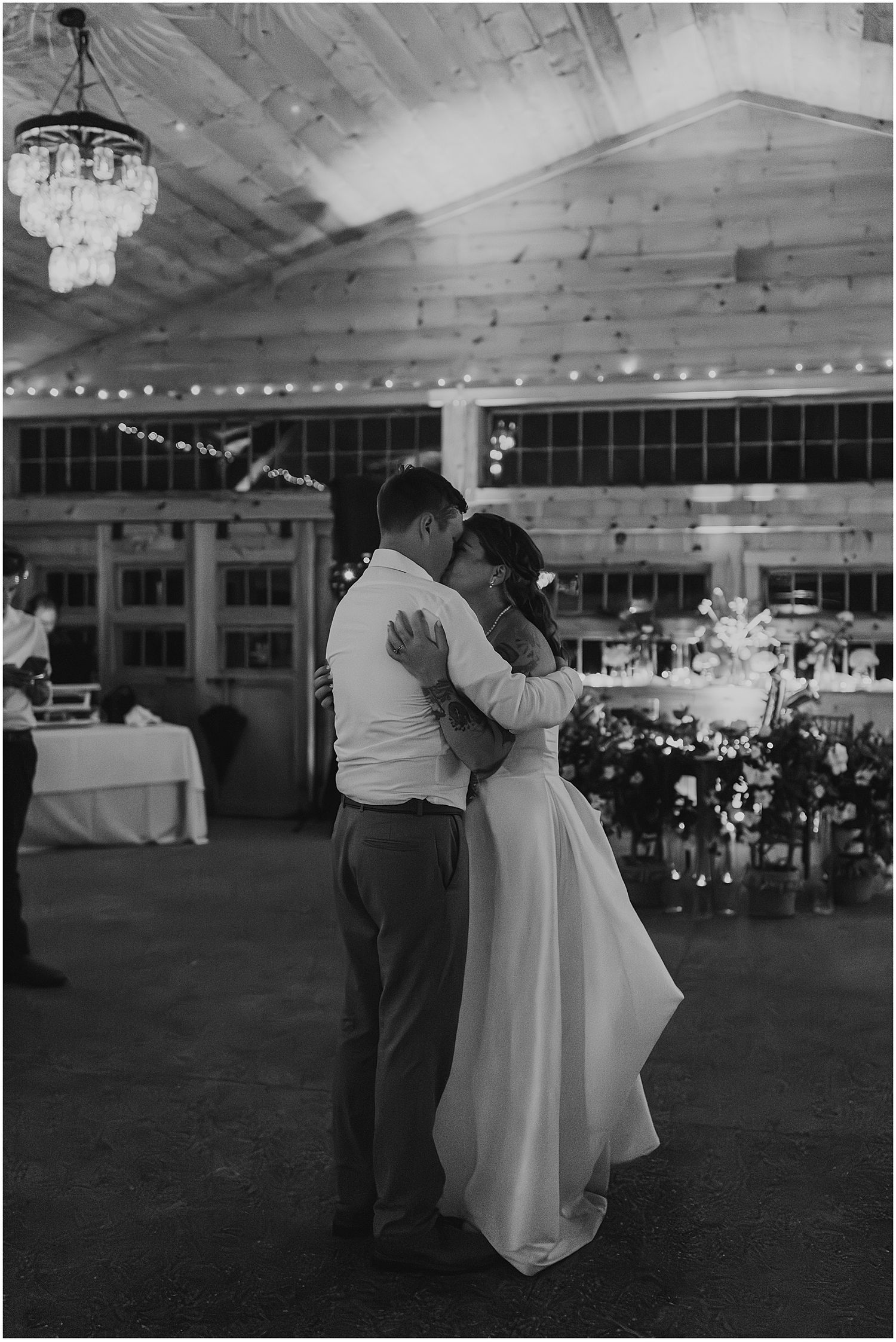 Black and white wedding reception dance captured under string lights in an elegant indoor venue.