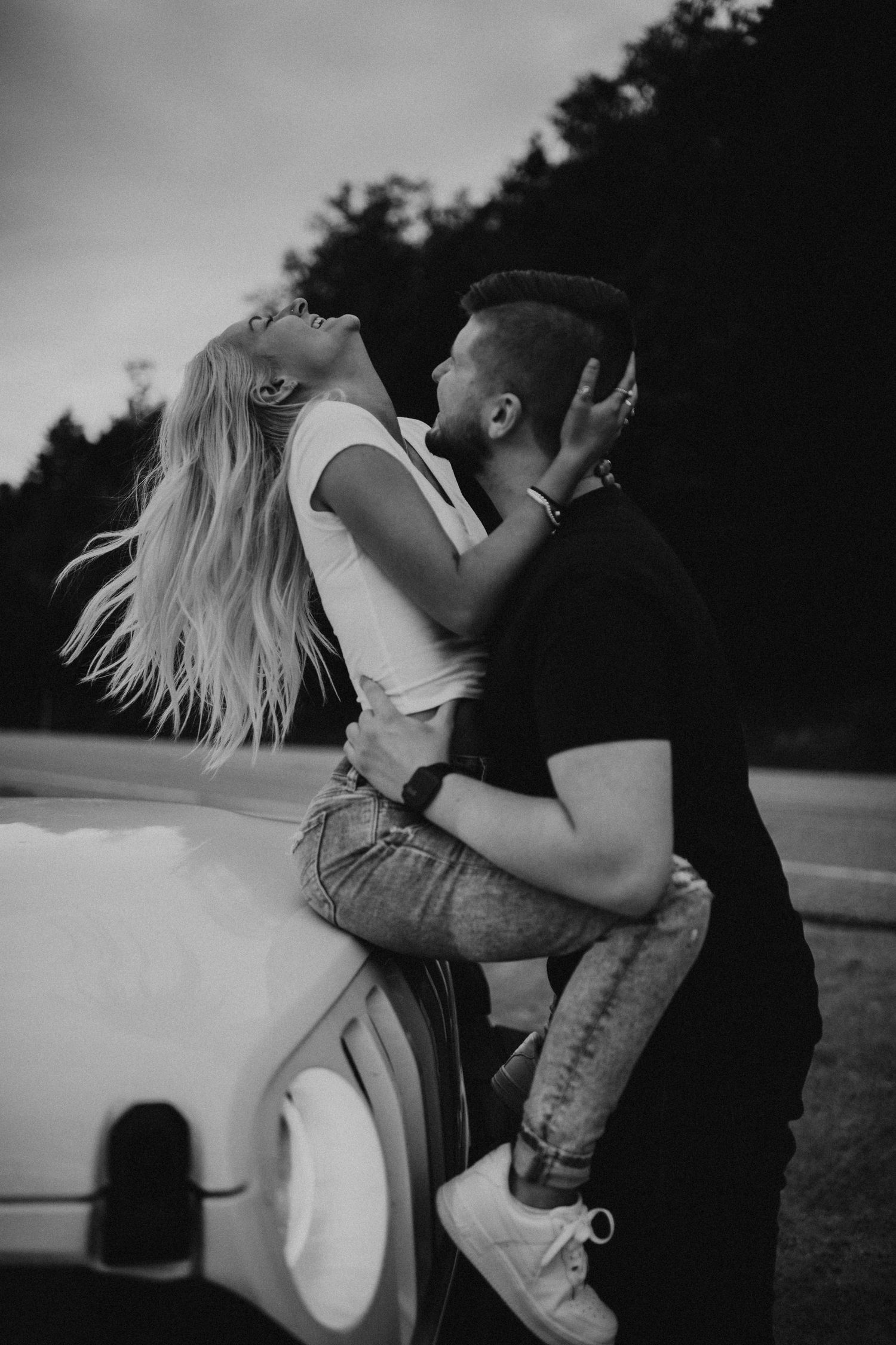 Paige and Justin embracing each other playfully during sunset on the Kancamagus Highway in New Hampshire.