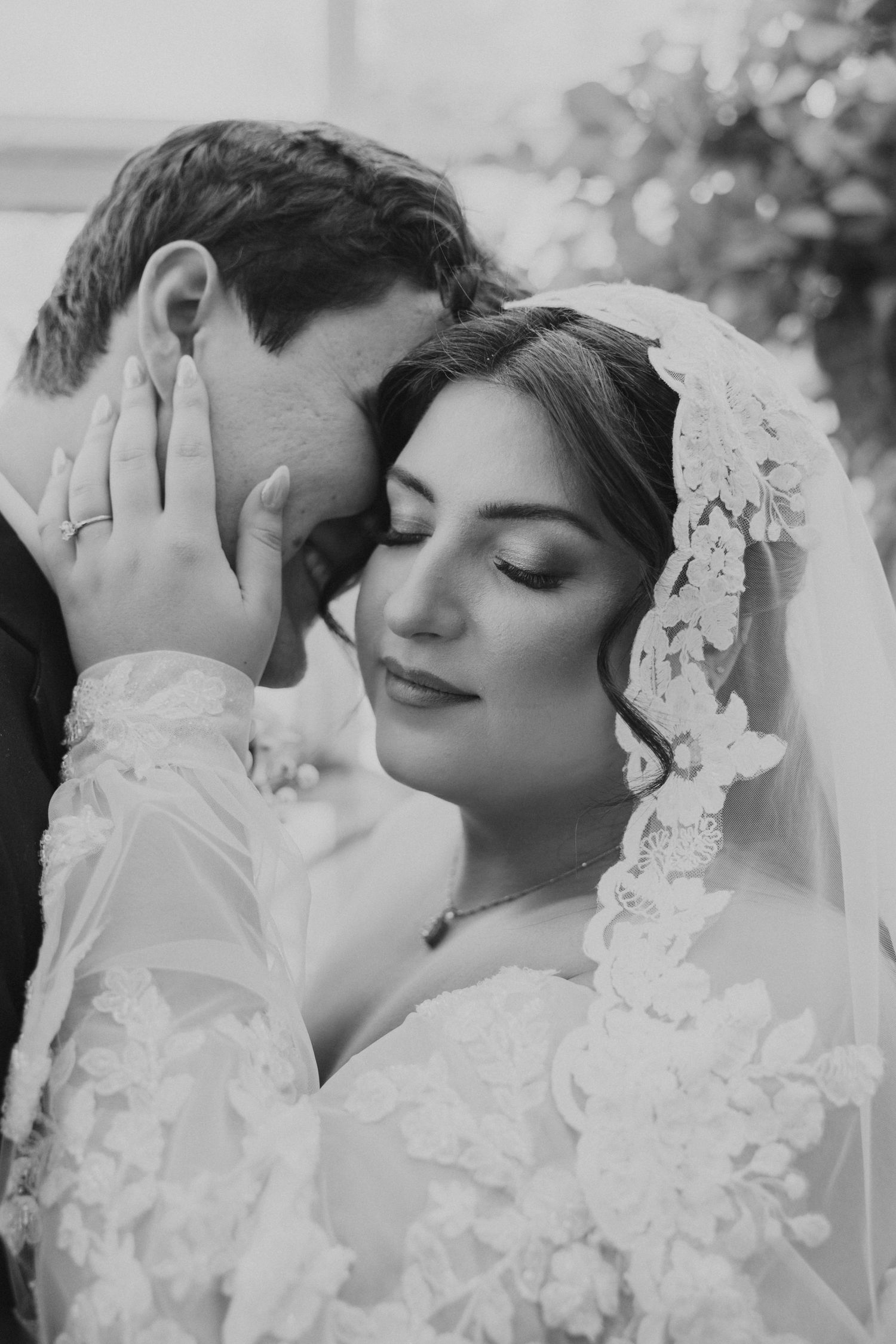 Intimate black and white portrait of bride and groom embracing closely on their wedding day.
