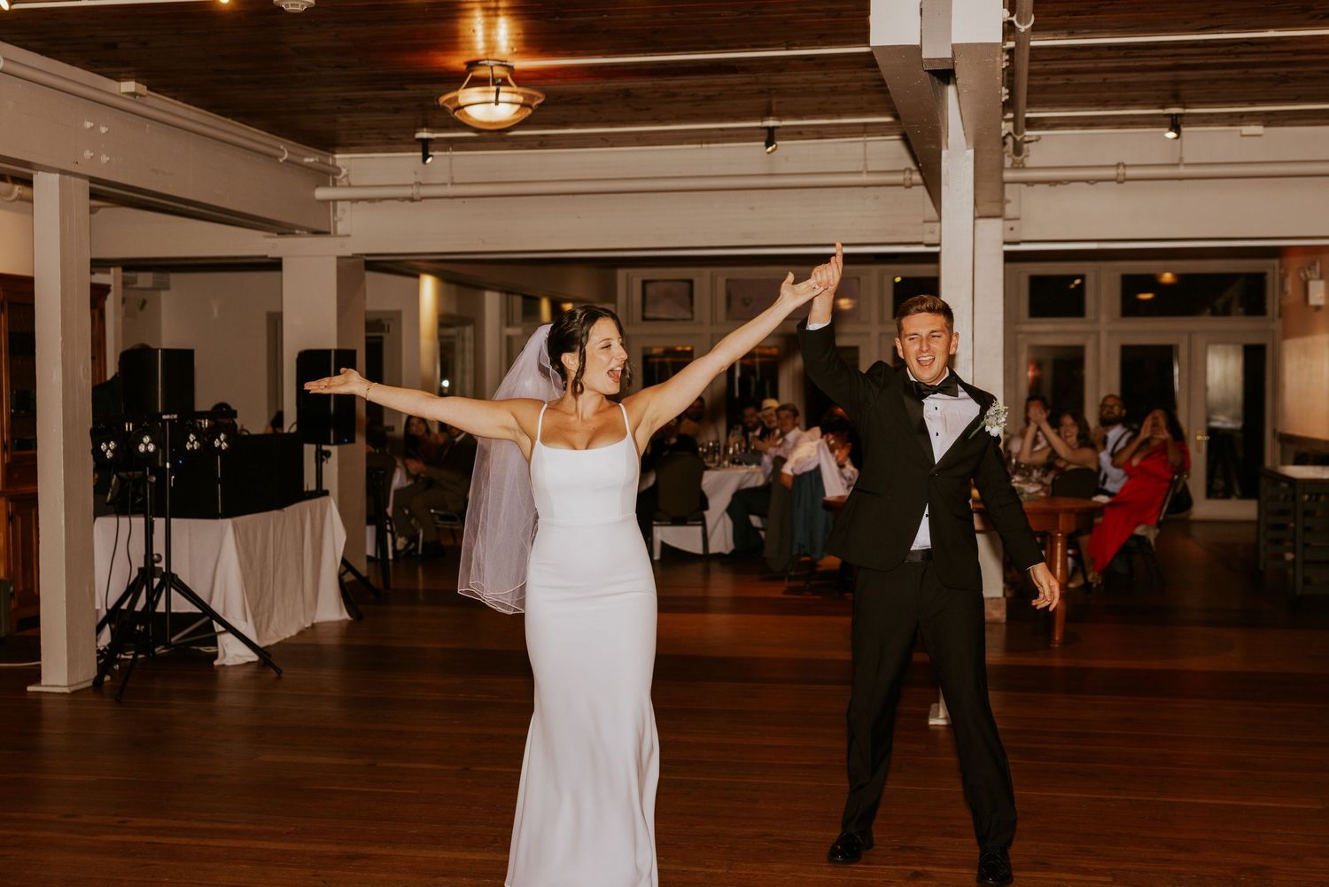 Bride and groom dancing together at wedding reception with guests watching.