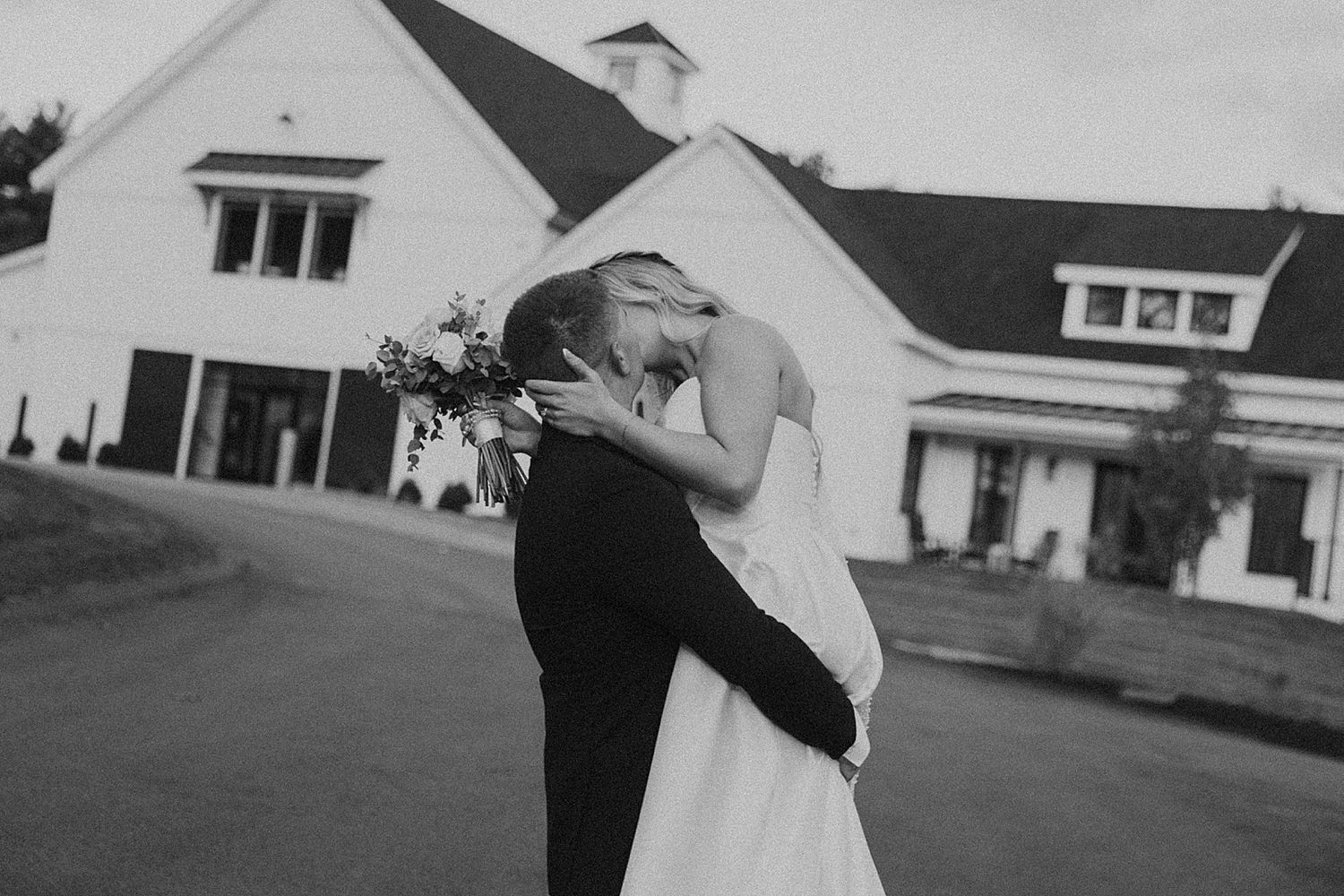Black and white image of a bride and groom kissing outside Hyla Brook Estate in NH