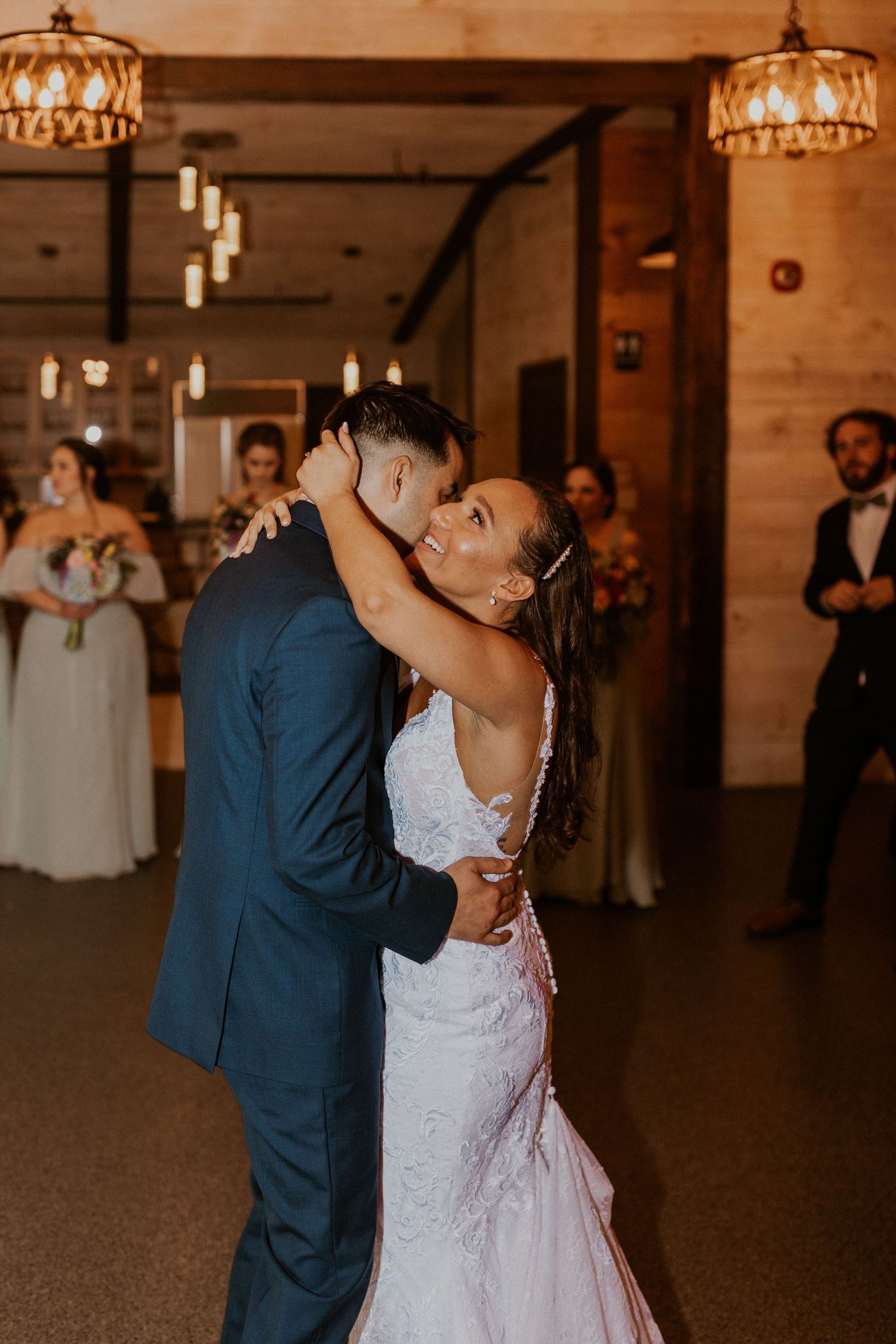 Romantic dance moment in a rustic barn wedding venue with warm lighting and wooden walls.