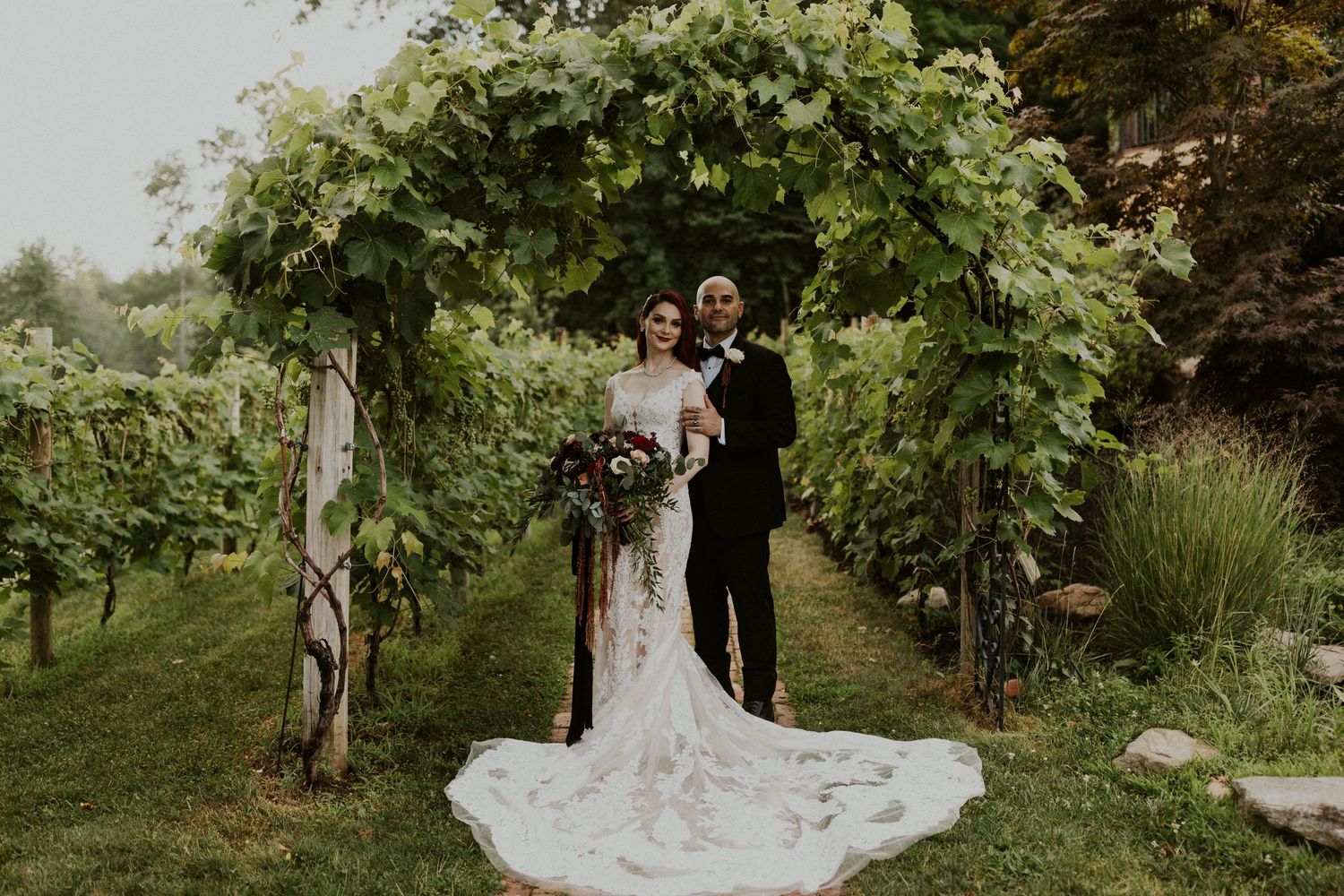 Bride and Groom posing under the grape vines at zorvino vineyards in Sandown NH.