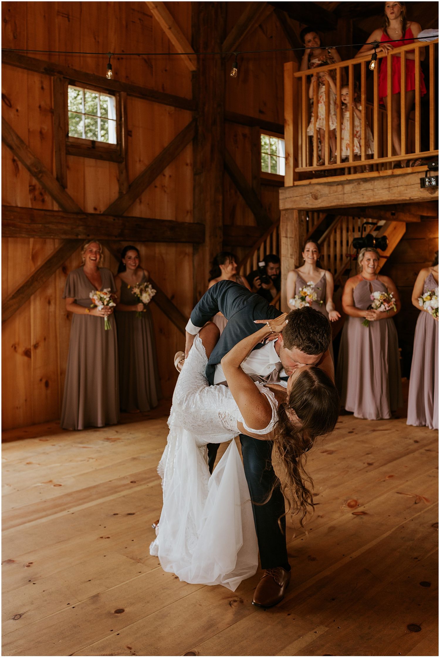 Dancing couple performs romantic dip move on wooden barn floor during celebration.