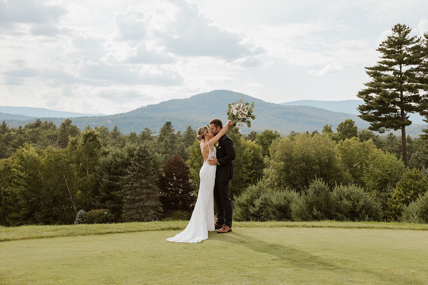 Bride and groom taking portrait photos outside at their Owl's Nest wedding in NH with the White Mountains in the background