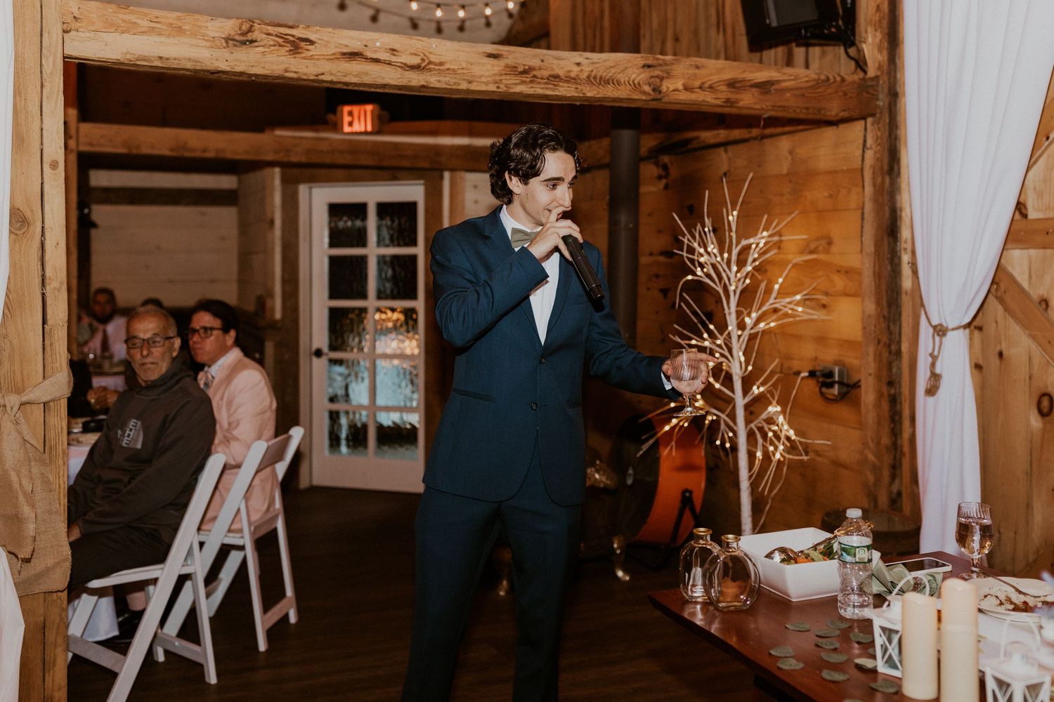 Elegant rustic barn interior decorated with white curtains and wooden beams for a wedding celebration.