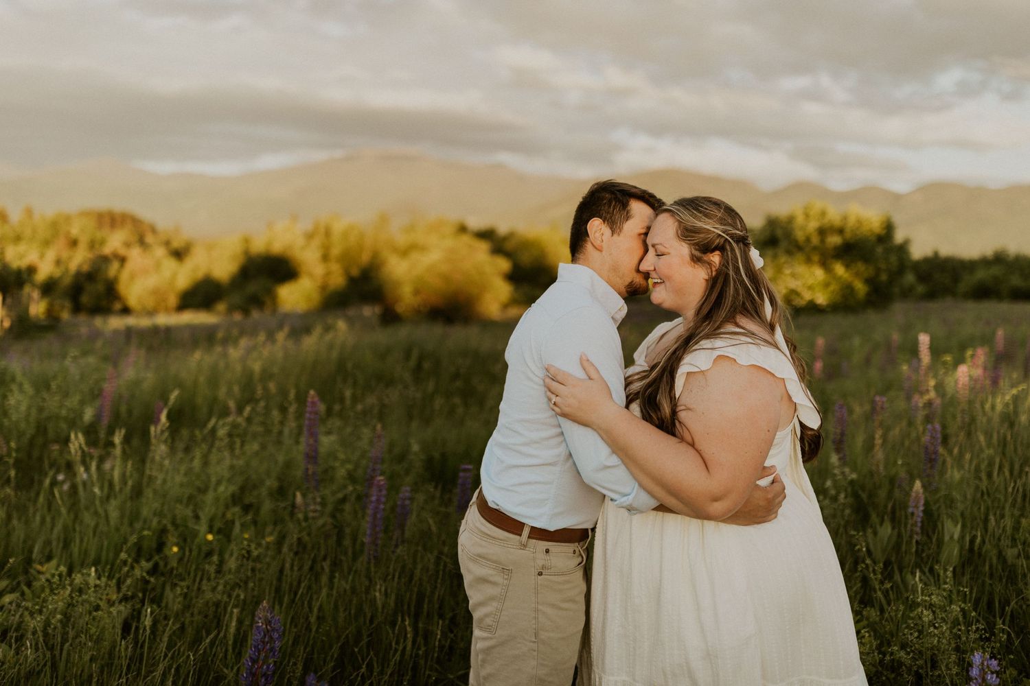 Terise and Jose embracing each other in the purple lupine fields of Sugar Hill New Hampshire.