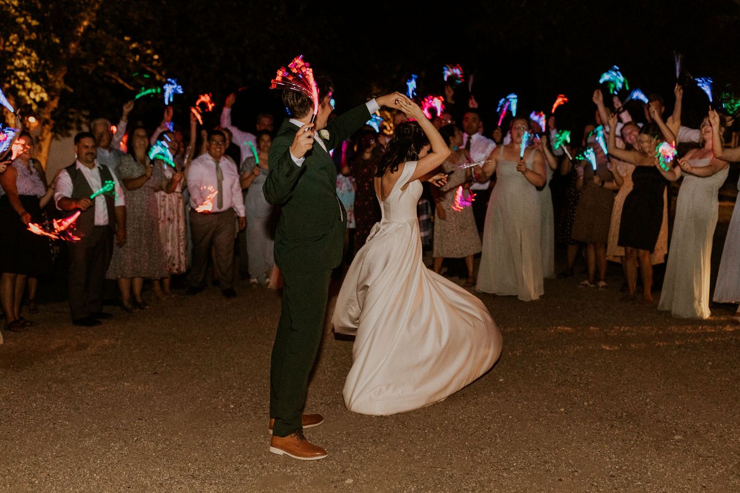 Colorful glow sticks illuminate a lively wedding dance floor celebration.