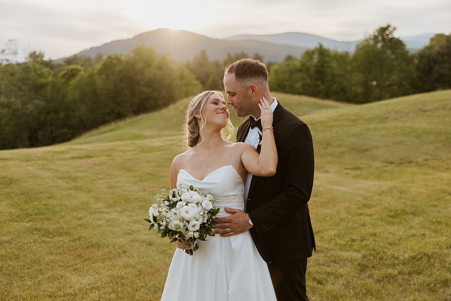 Bride and groom taking sunset portrait photos with the mountains in the background at their New Hampshire wedding