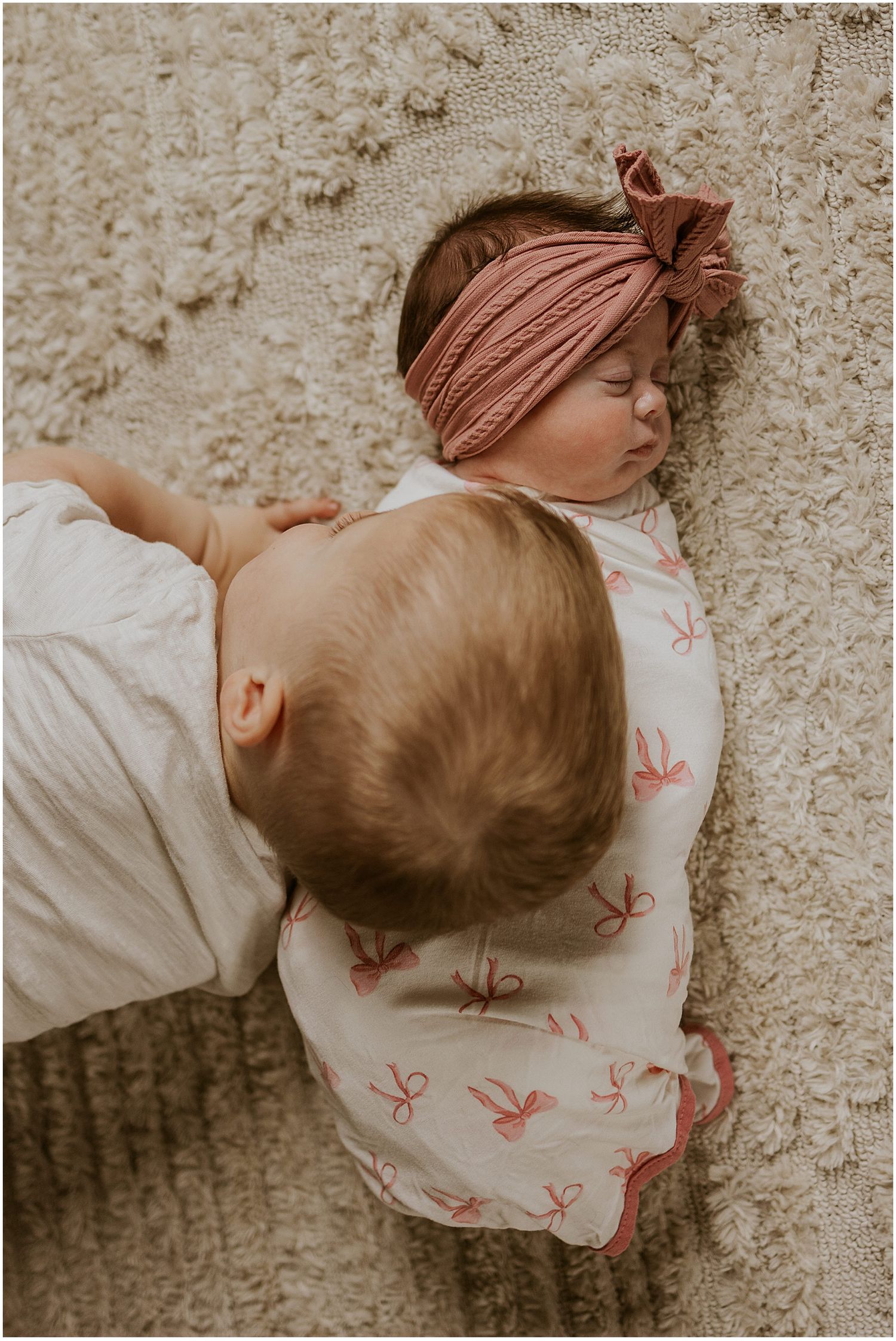 Toddler cuddling his newborn baby sister while she sleeps