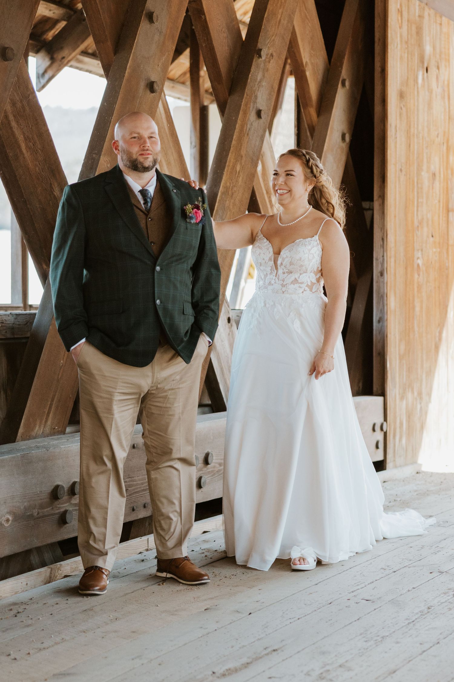 Close-up view of formal shoes and wedding attire on wooden bridge floor.