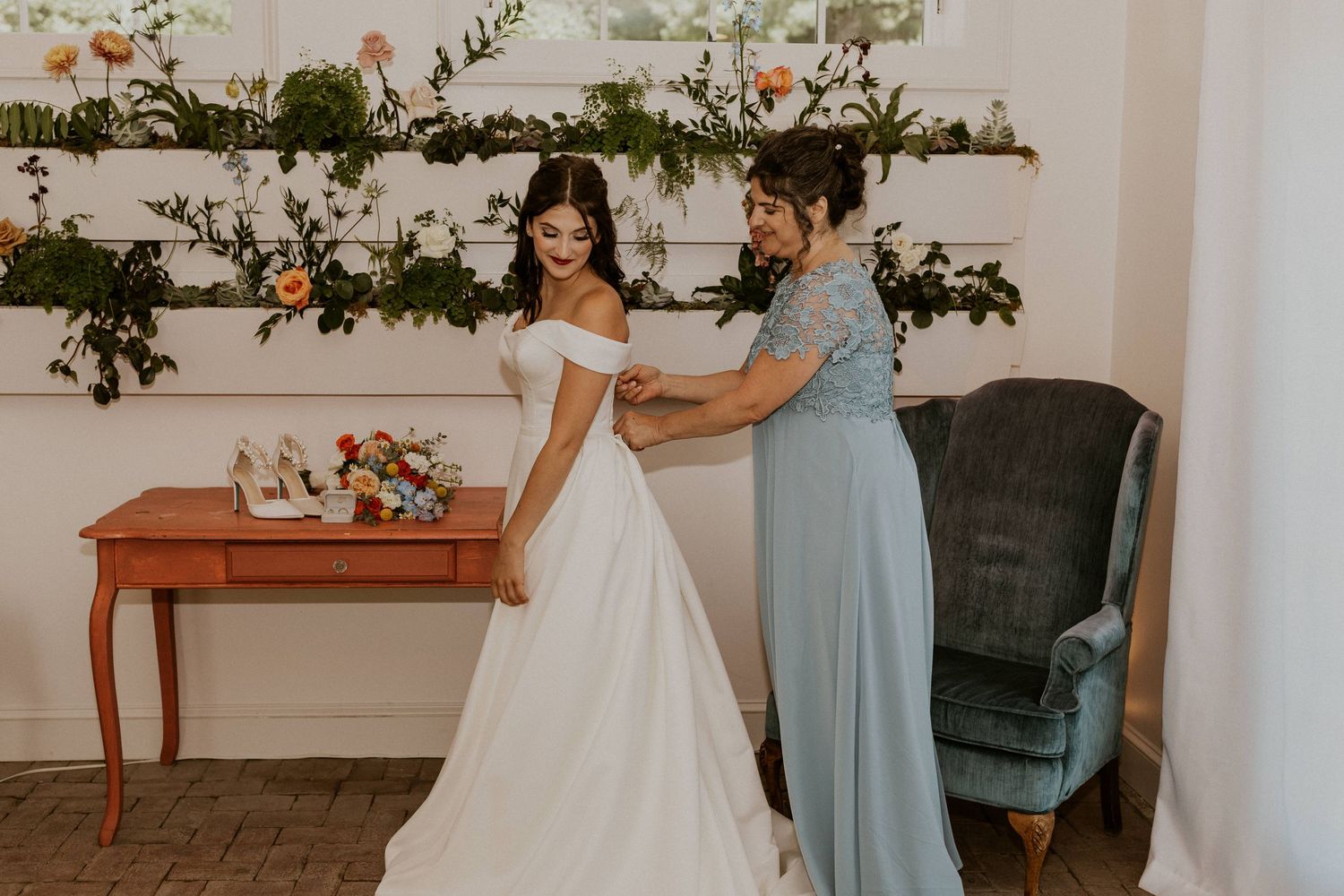 Elegant bridal scene with light blue bridesmaid dresses and floral decorations in a bright indoor setting.