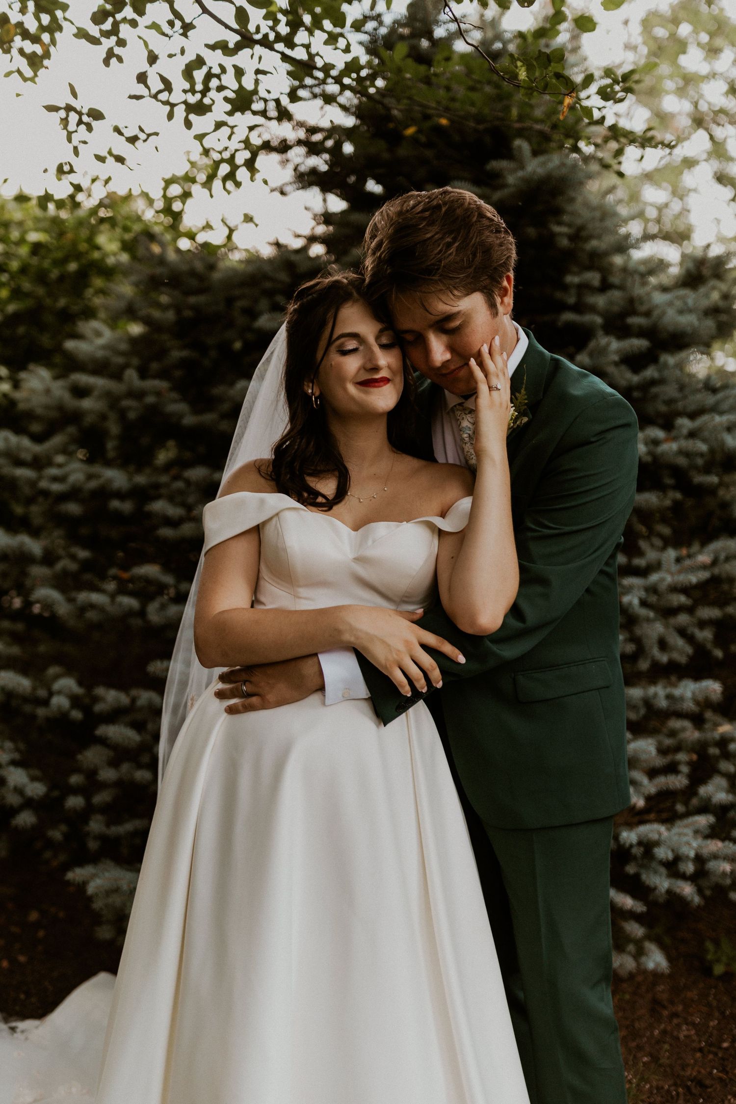 Tender wedding moment captured against natural garden backdrop.