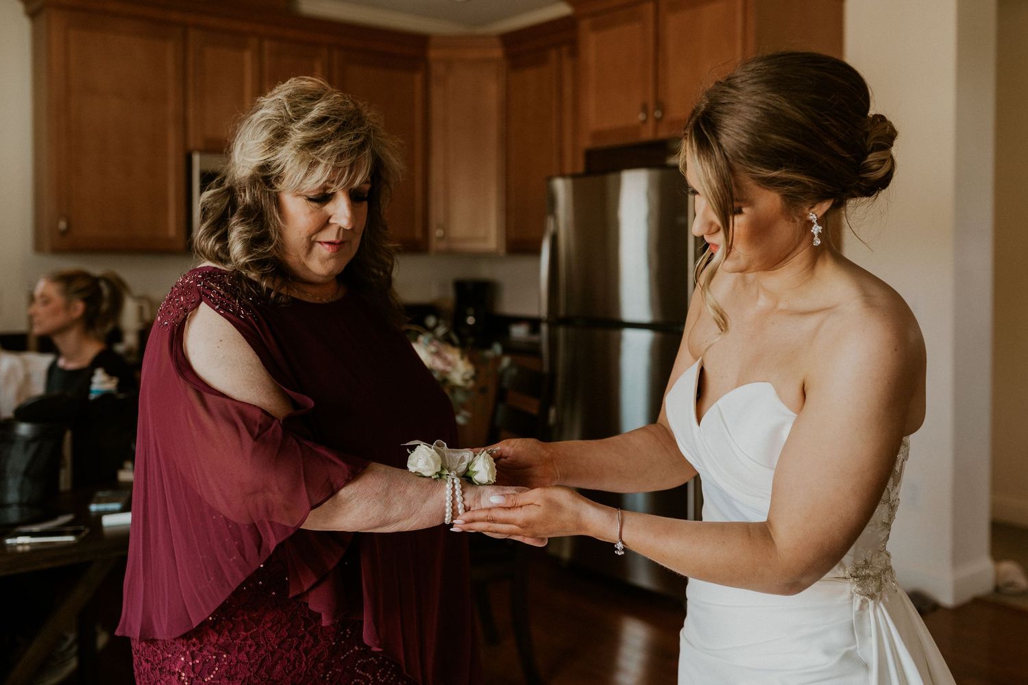 Kendra placing her mothers corsage on her wrist while getting ready for the wedding at Owl's Nest.