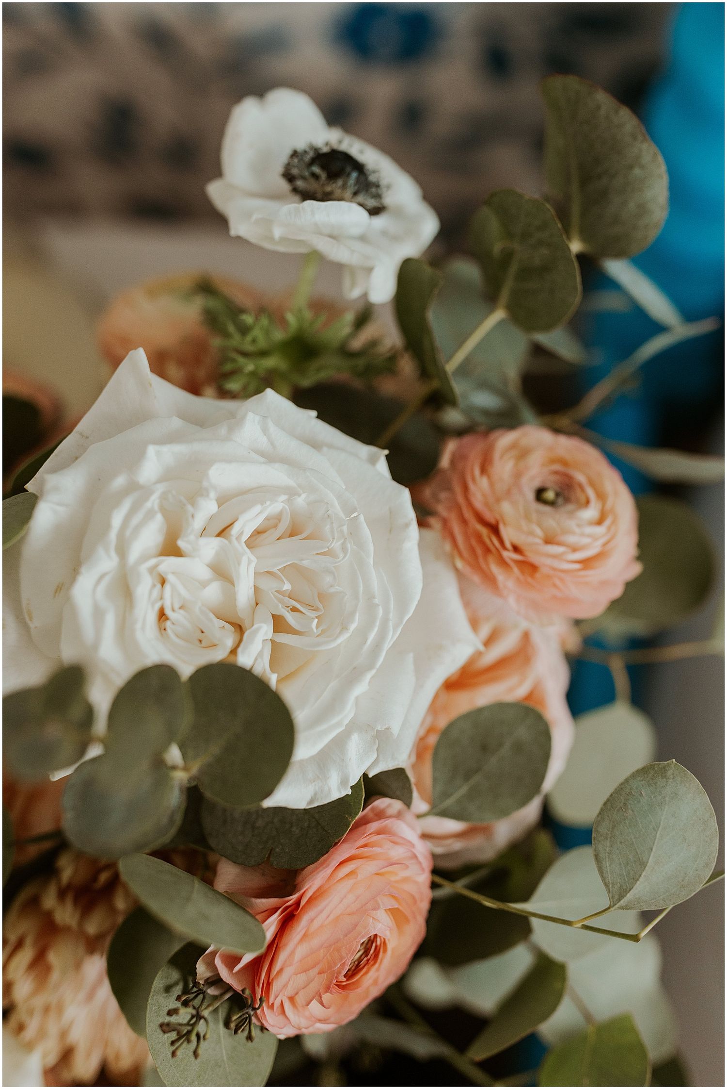 Delicate floral arrangement with white roses, peach ranunculus, and eucalyptus leaves.