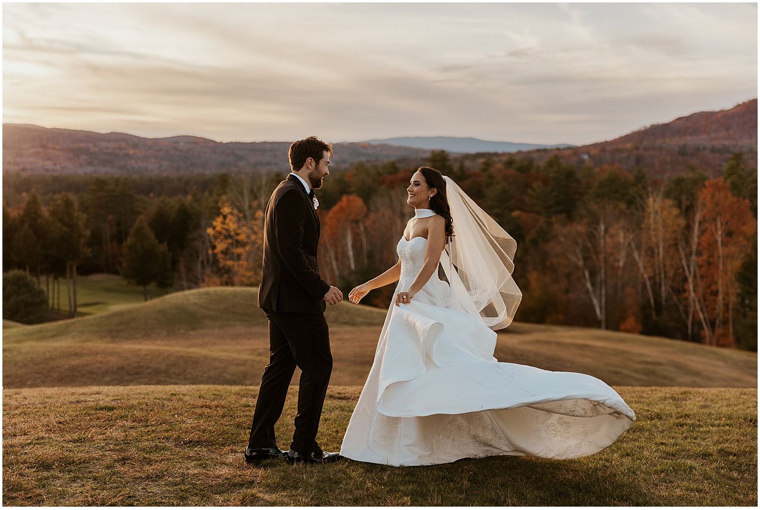 Panoramic landscape view of wedding couple on rolling hills at sunset.