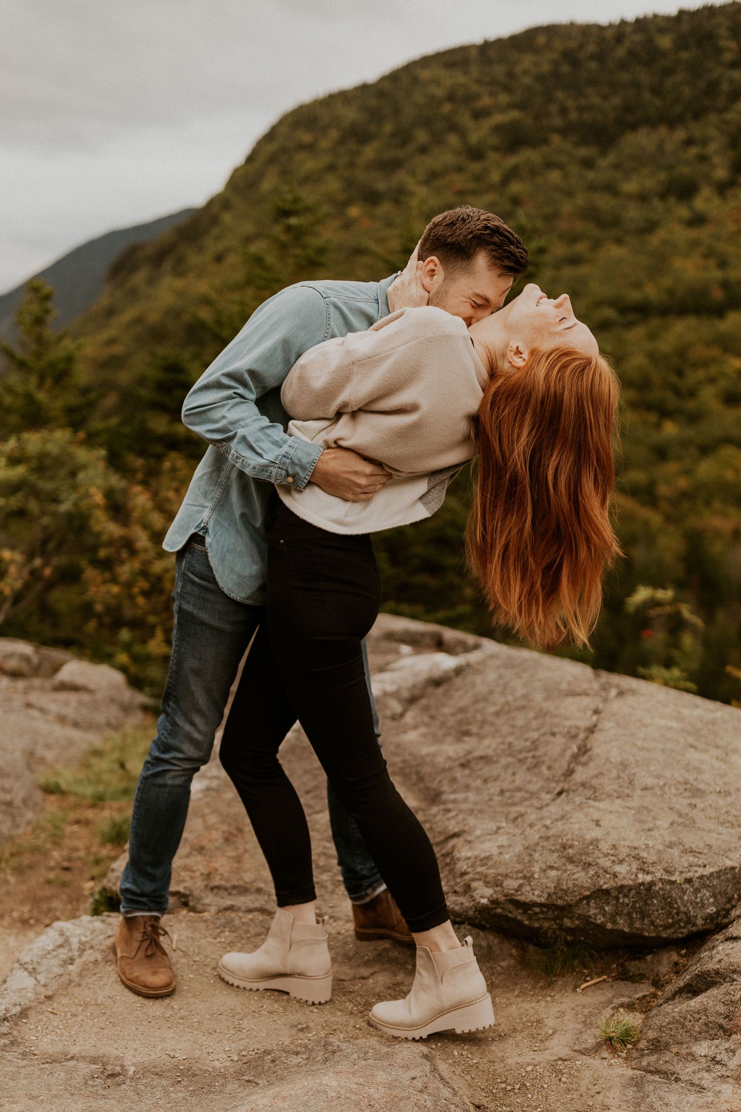 Sam and Colin playfully embracing each other on a mountaintop in New Hampshire during their adventure engagement session