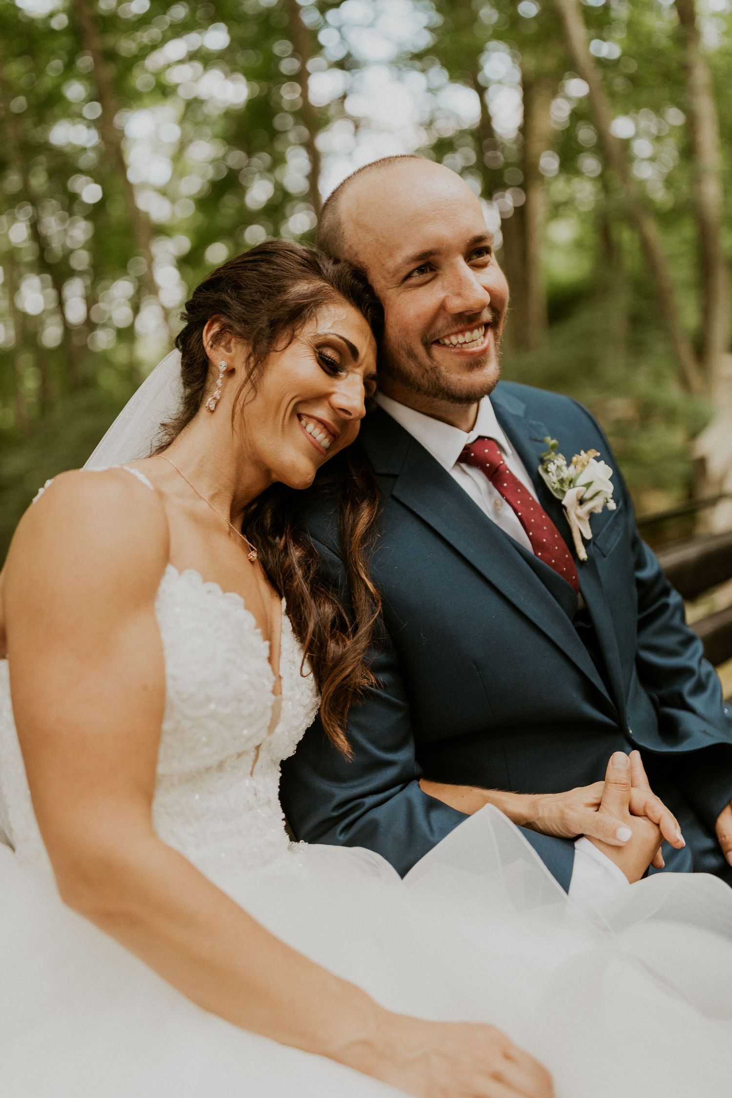 Newlyweds share a joyful moment while riding in a horse-drawn carriage through a forest.