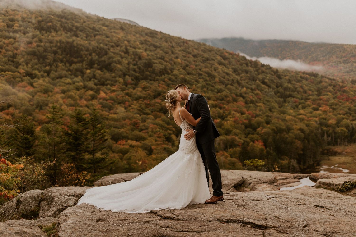 Husband and wife sharing their first kiss on the mountain top in the white mountain national forest of New Hampshire.