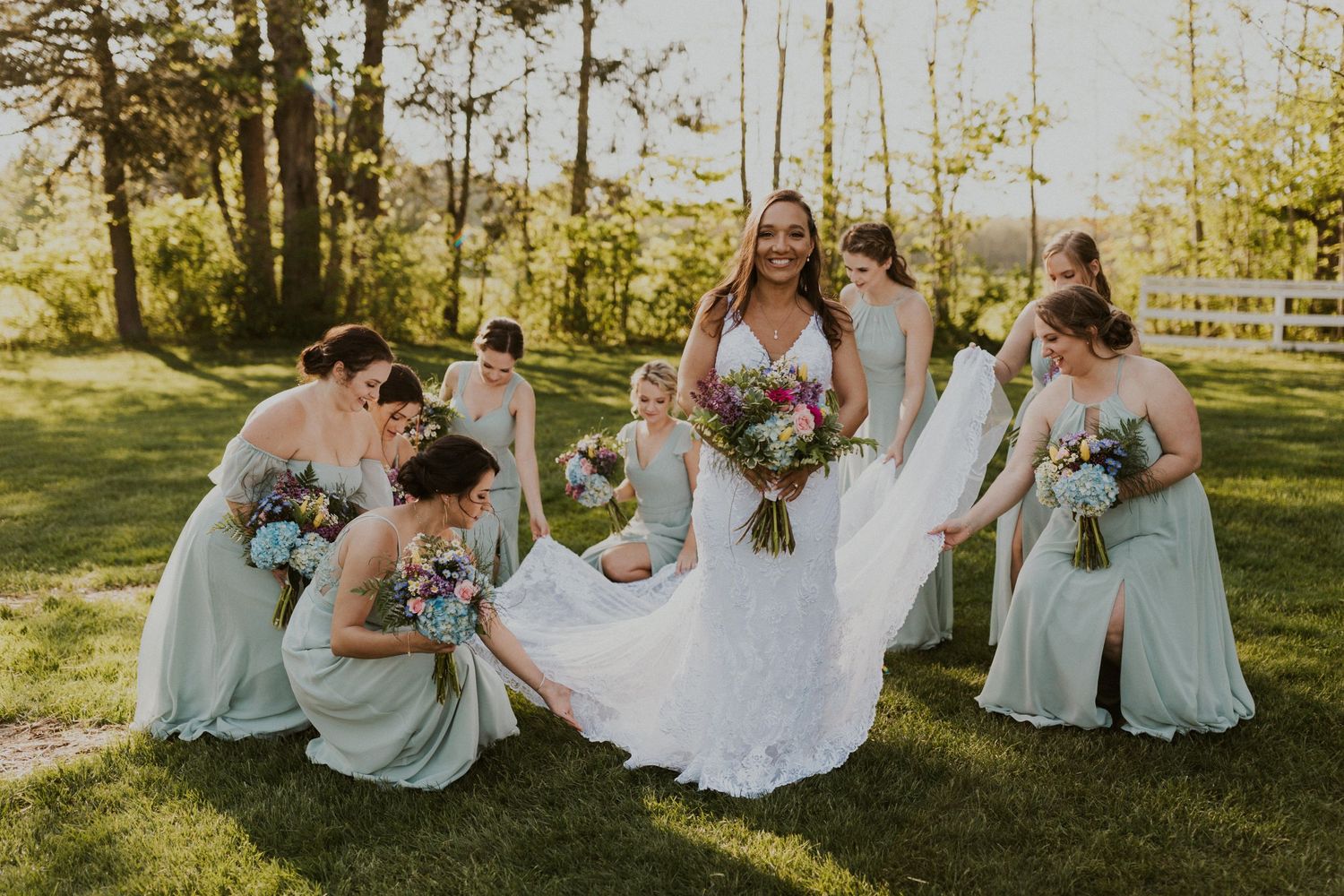 All of the bridesmaids adjusting Chrissy's wedding gown.