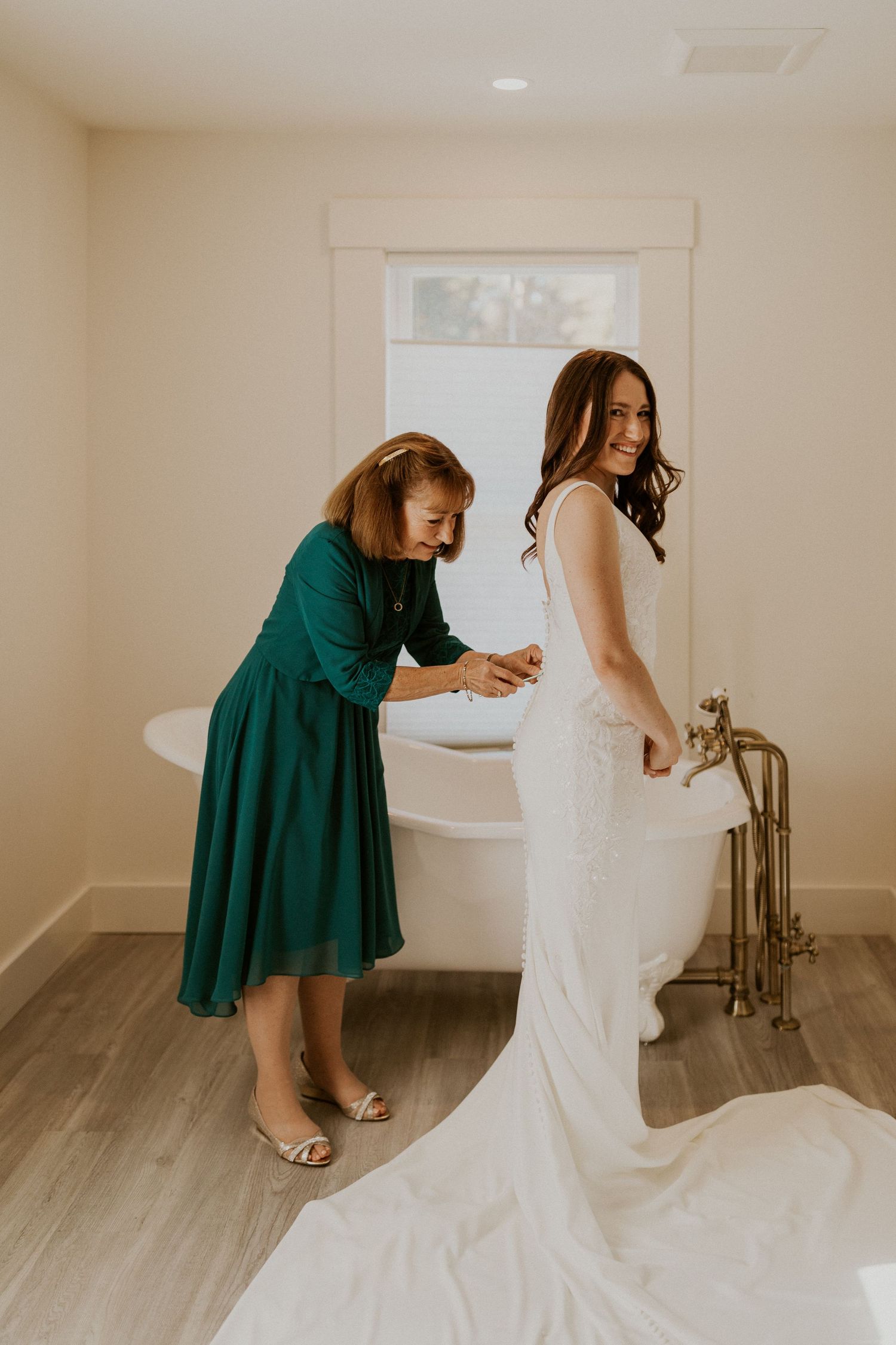 Briana's mom helping button her wedding gown while getting ready at the Woodstock Farmhouse in New Hampshire.
